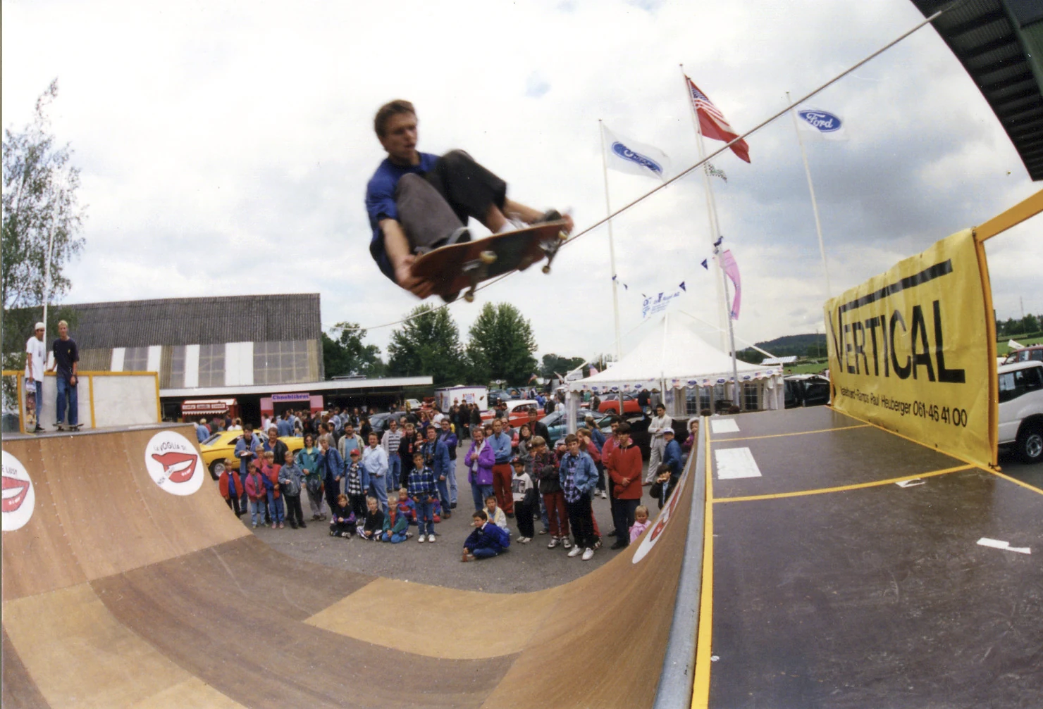 Skateboarder beim Frontside Double Grab über der demontierbaren Minirampe von Vertical Technik in Dielsdorf, vor Publikum.