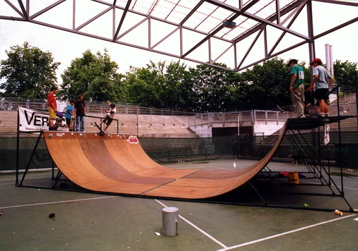 Demontierbare Minirampe von Vertical Technik 1991 mit brauner Fahrfläche und Skateboardern unter einer offenen Dachkonstruktion.