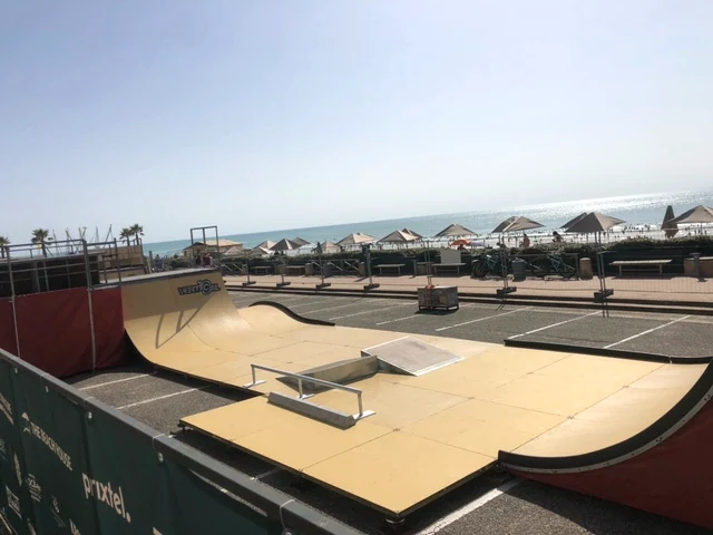 Übersicht der mobilen Skateanlage mit Quarterpipes, Rails und Funbox auf einem Parkplatz am Meer.