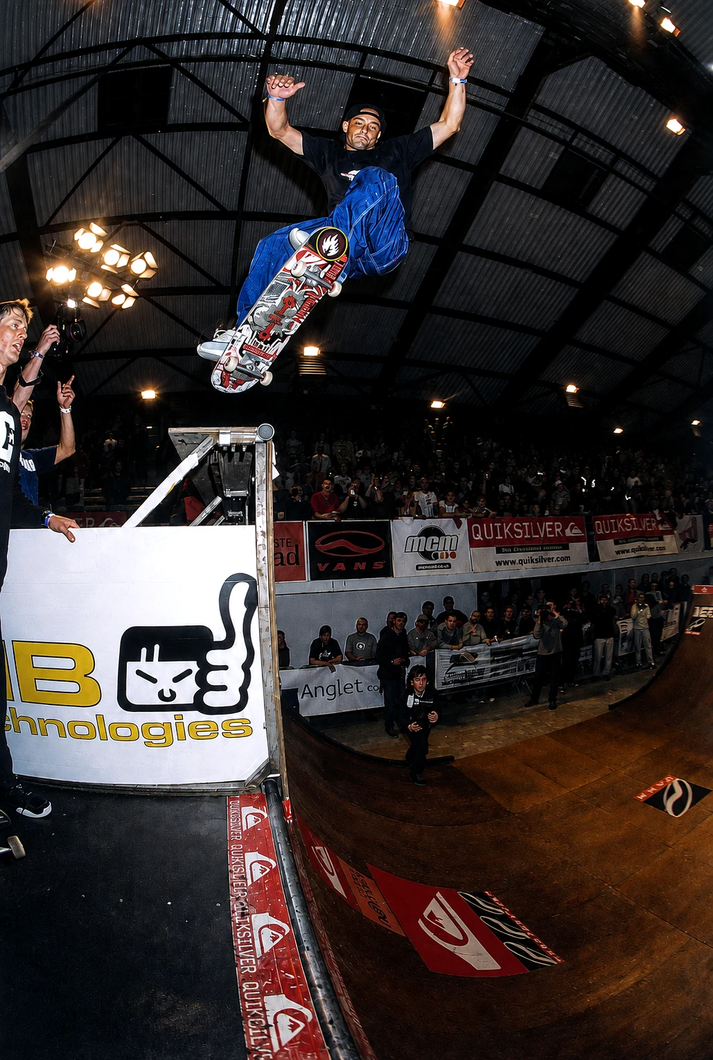 Omar Hassan bei einem Ollie von der Extension zur Rampe auf der Glissexpo Paris 2001 in einer dunklen Eventhalle.